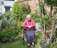 Elderly woman sitting on her walker in her garden