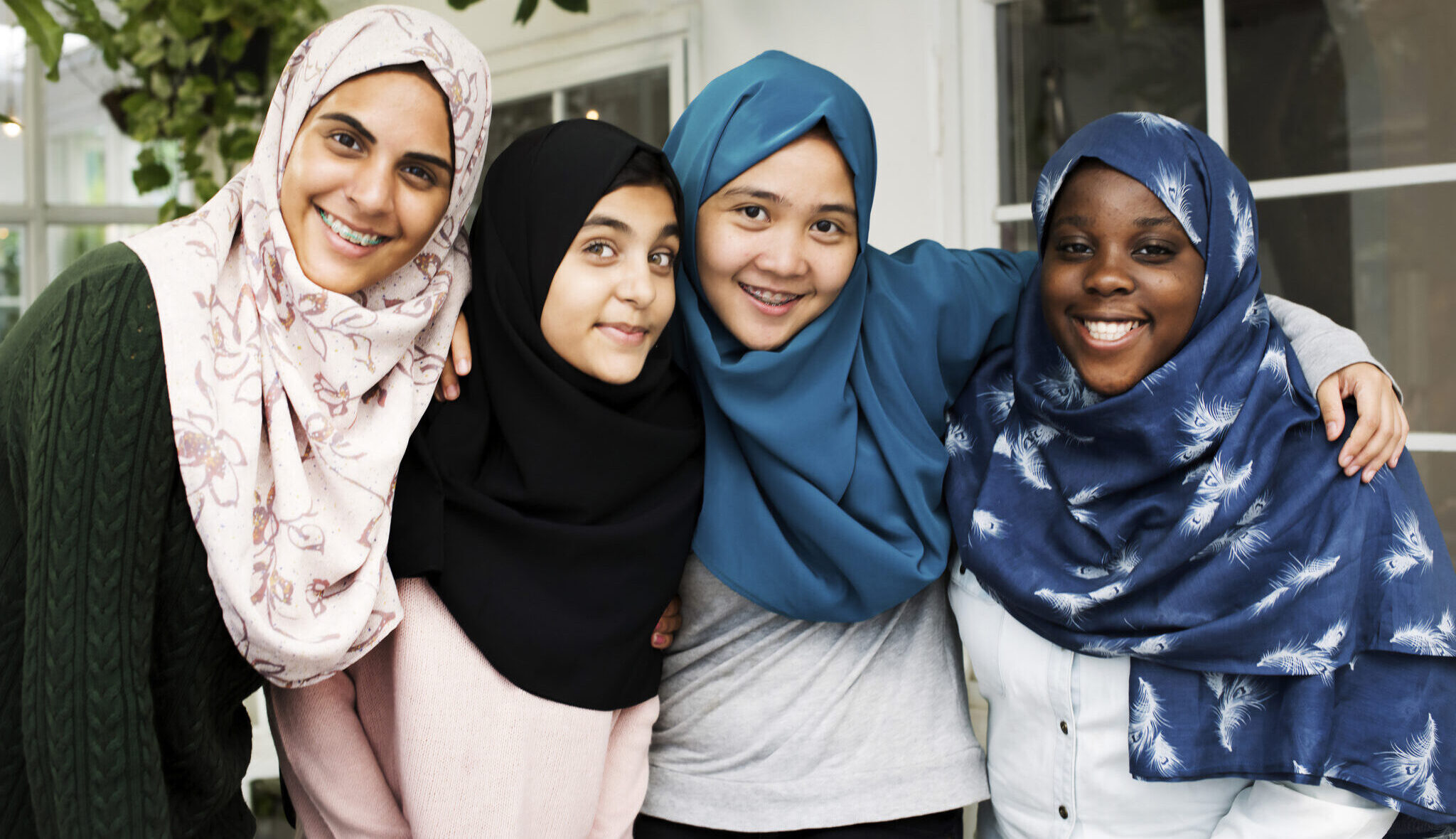 Group of 4 girls wearing hijabs hugging