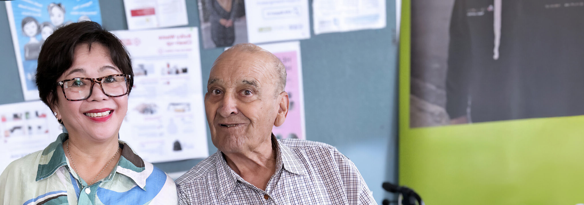 Smiling volunteer standing beside a social group client; both are looking at the camera and appear happy
