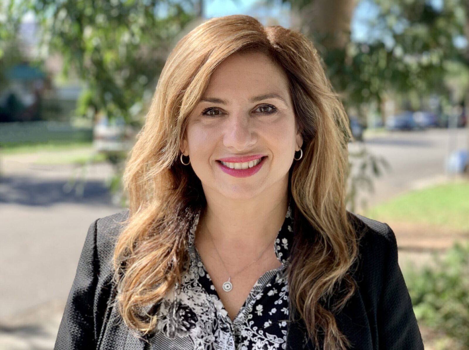 Portrait photo of CEO, Esta, smiling outside the Community Centre