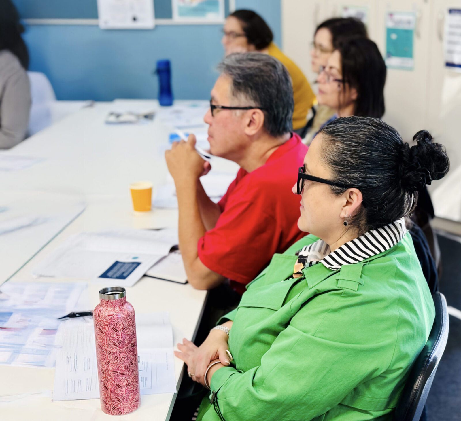 Group of women and one man seated in a classroom, engaged in learning